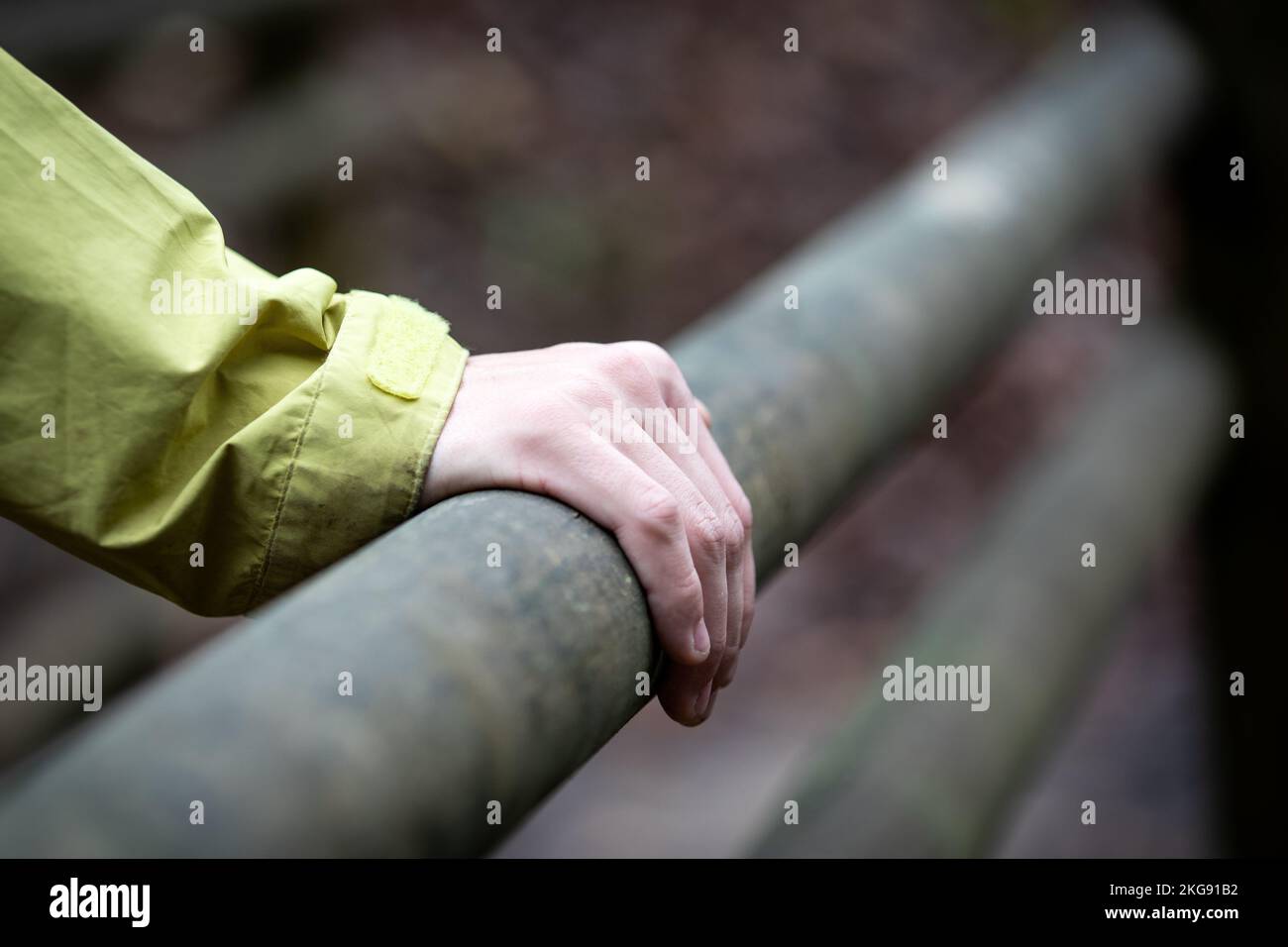 Close-up of hand on wooden railing outdoors , blured background. Stock Photo