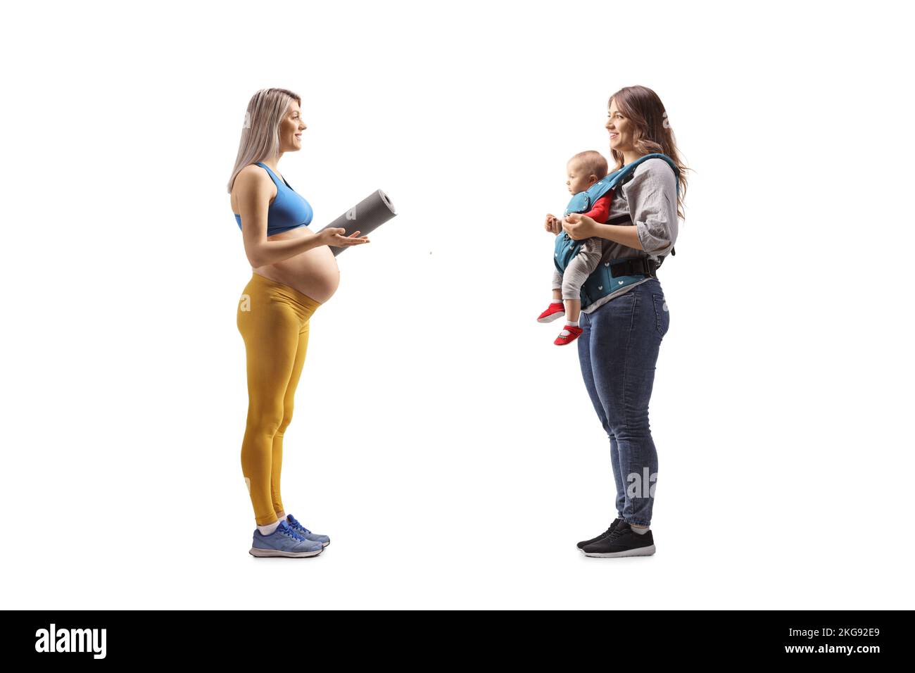 Full length profile shot of a pregnant woman in sportswear talking to a woman with a baby isolated on white background Stock Photo