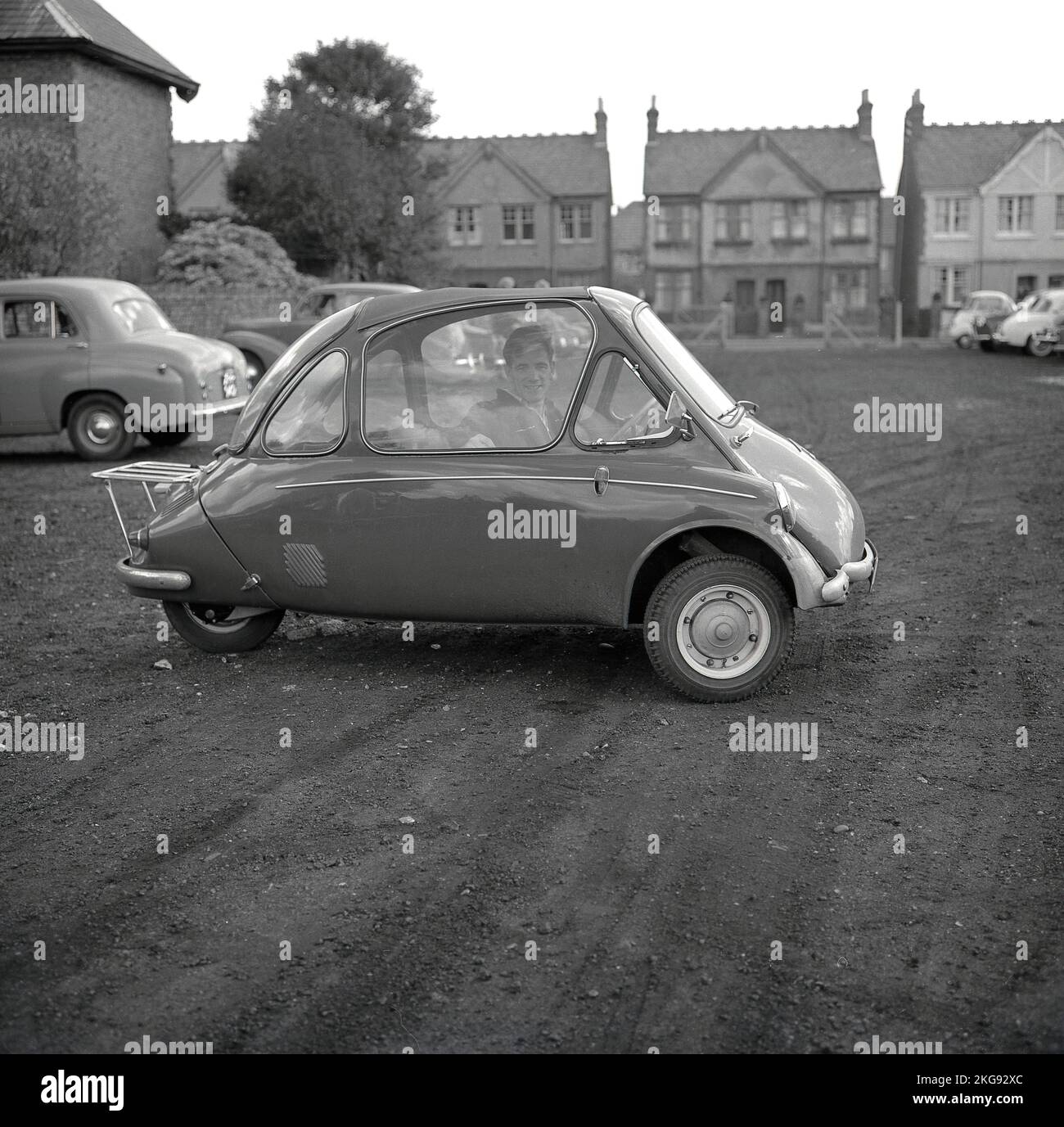 1960s, historical, outside in a gravel car park, a man sitting inside a small car of the era, a bubble car, a BMW Isetta, which had a front-opening door, Wycombe, England, UK. First built by Iso SpA in Italy in 1953, this tiny car was built under licence in different countries, including by BMW of Germany until 1962 and famously known as the 'Bubble Car'. Stock Photo