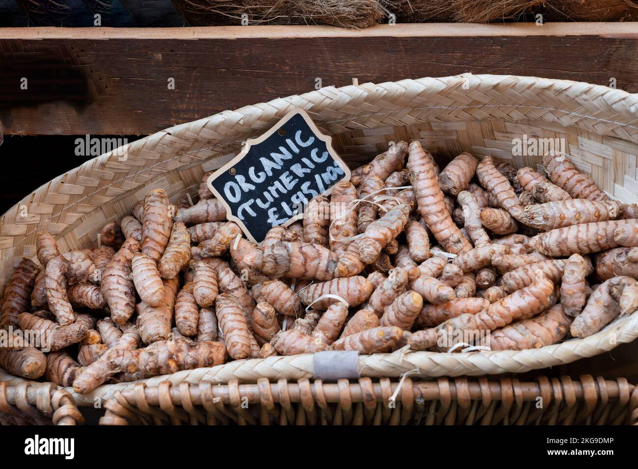 A basket display of organic fresh turmeric, Curcuma longa, for sale on a market stall. The turmeric is loose and priced for the consumer Stock Photo