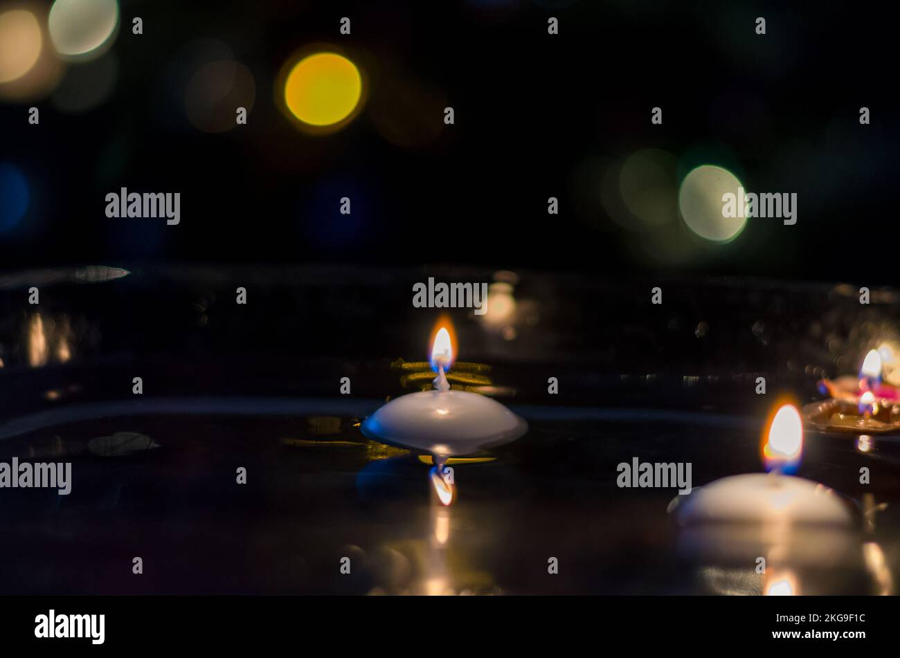 nutshell with burning candles floating on water surface in dark