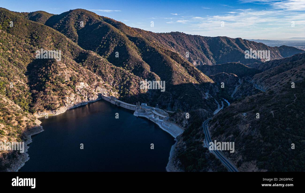 An aerial of a large water reservoir in the middle of green hills Stock