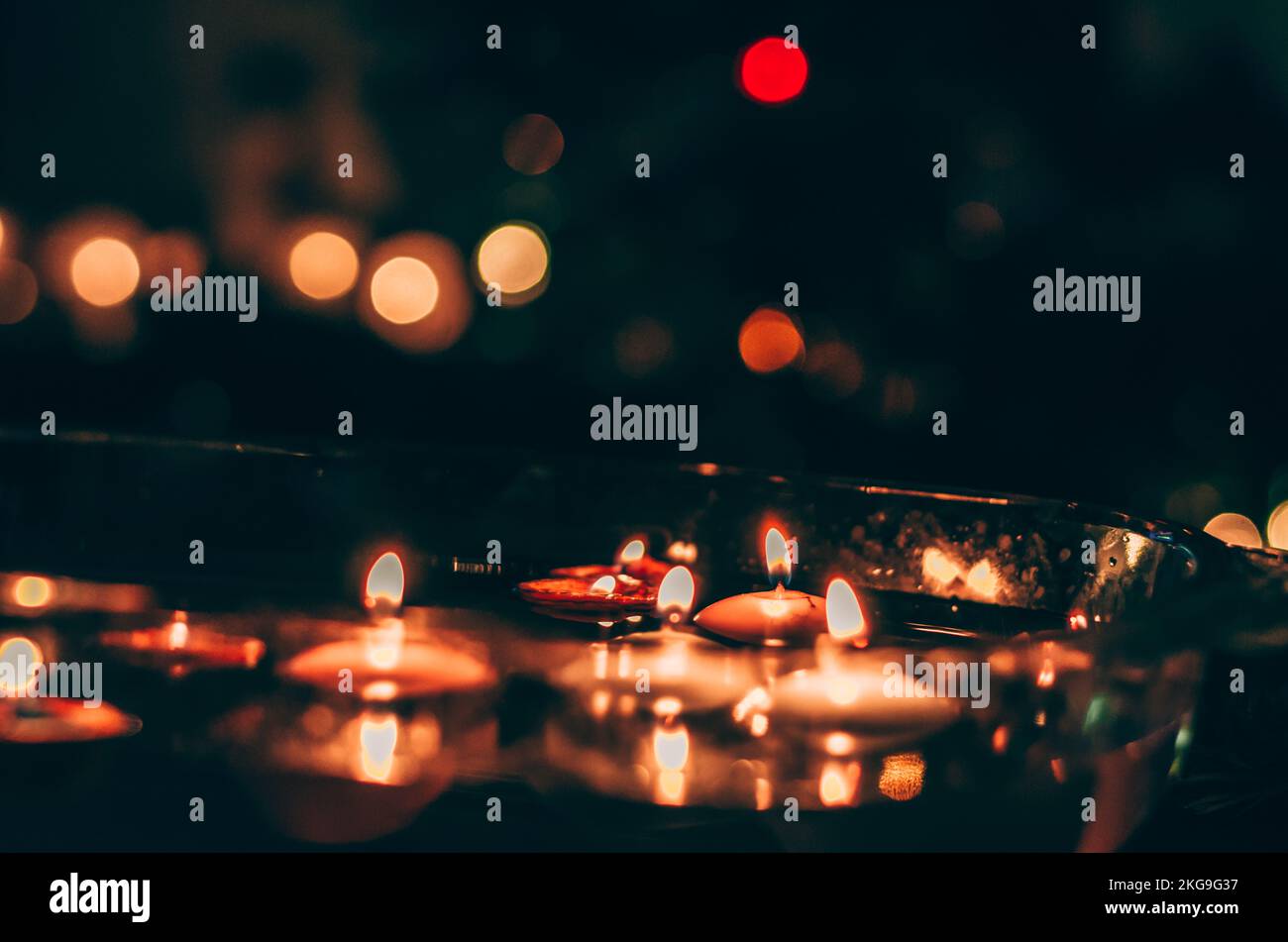 burning candles floating on water surface in dark, European christmas
