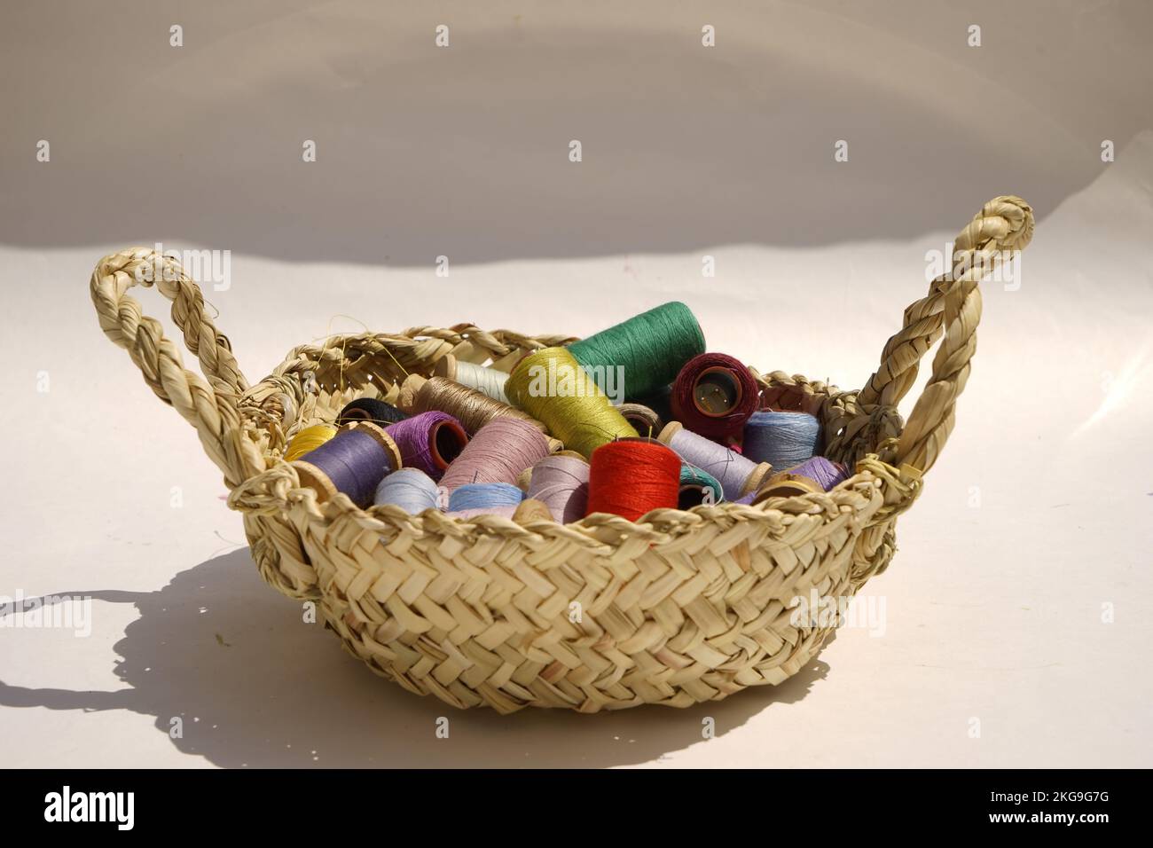 Wicker basket with balls of knitting yarn on white background, close up ...