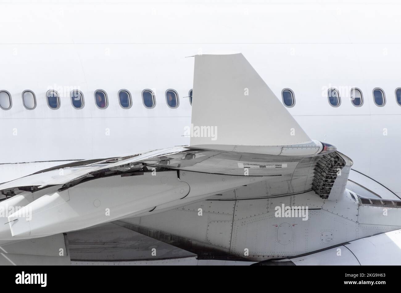 View of the wing tip of the aircraft and the fuselage with portholes. Stock Photo