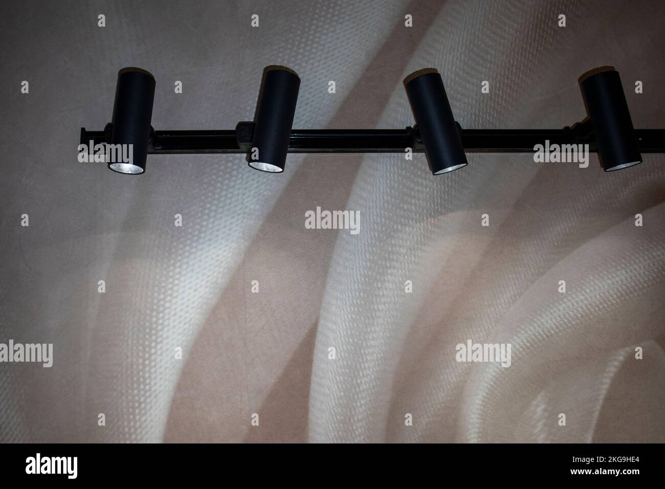 black modern lamps in the shape of a cylinder illuminate the wall Stock Photo