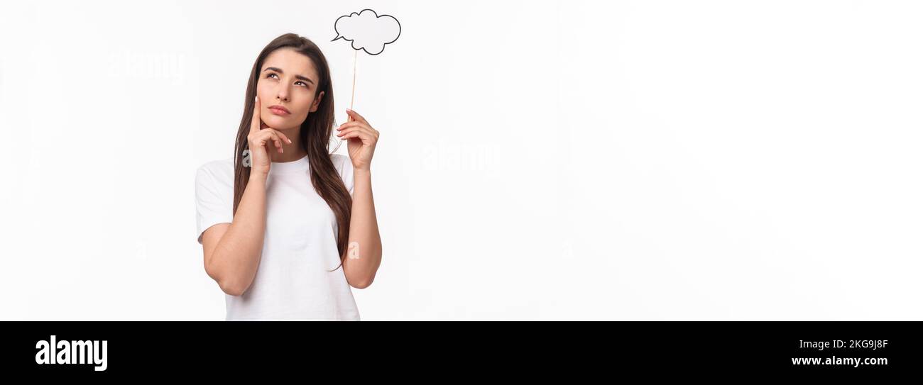 Entertainment, fun and holidays concept. Portrait of thoughtful and creative young woman searching inspiration, holding thinking cloud near head Stock Photo