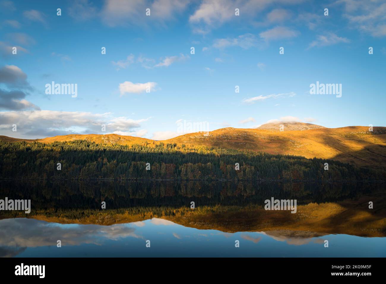 A sunny, still autumnal HDR image of reflections hills and forest in Loch More in the Reay Forest, northwest Sutherland, Scotland. 24 October 2022 Stock Photo