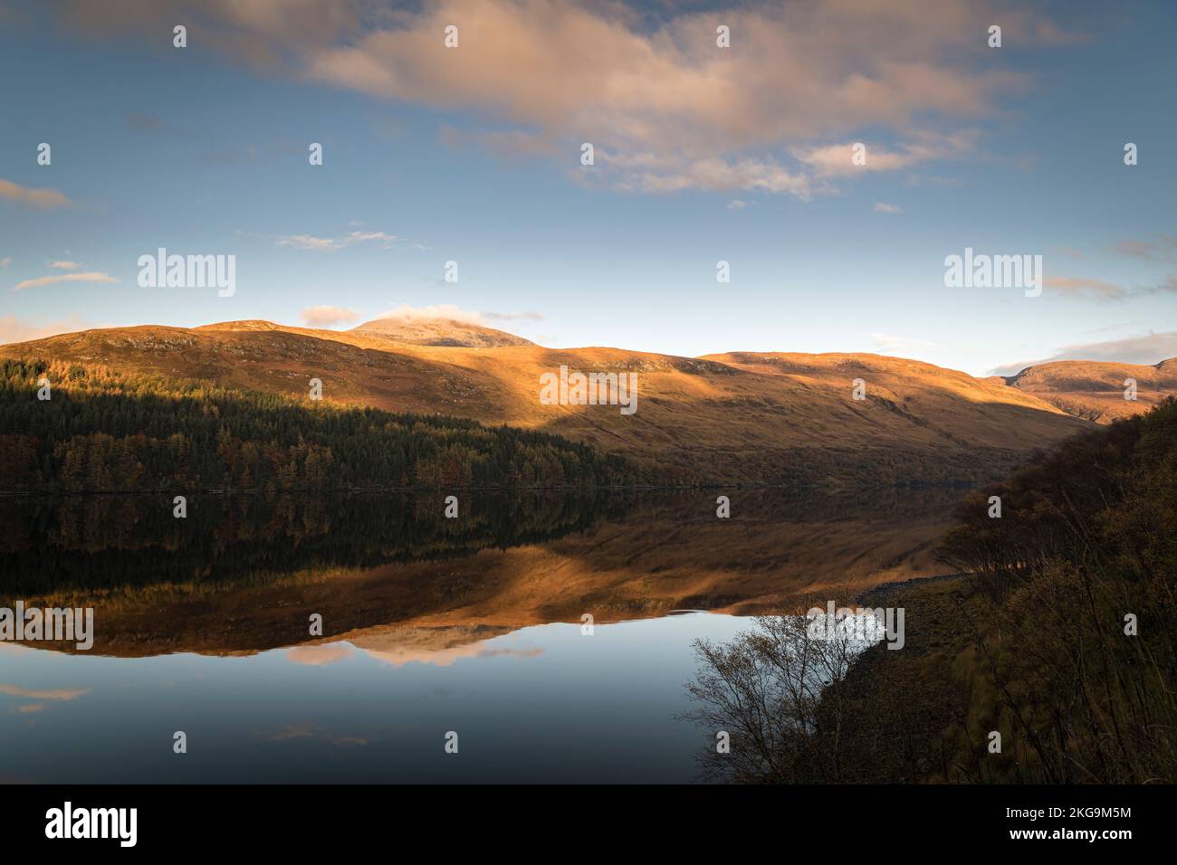 A sunny, still autumnal HDR image of reflections hills and forest in Loch More in the Reay Forest, northwest Sutherland, Scotland. 24 October 2022 Stock Photo