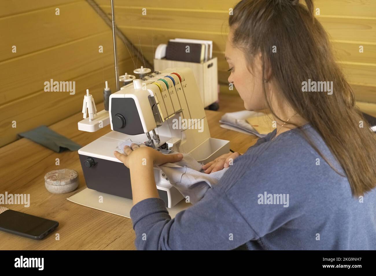 A woman designer works on an overlock sewing machine on tailoring