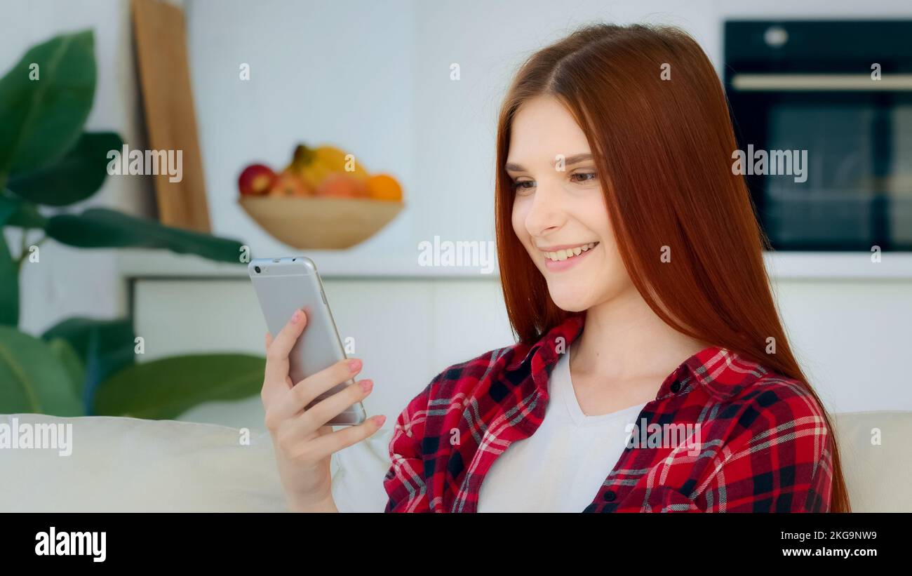 Attractive caucasian model girl taking selfie photo redhead young woman blogger recording video blog on telephone waving hello at mobile camera Stock Photo