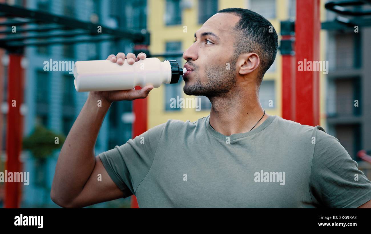 Athletic man latino american sportsman feel hot drink cold fresh water healthy protein beverage quench thirst in summer day hydration male body after Stock Photo