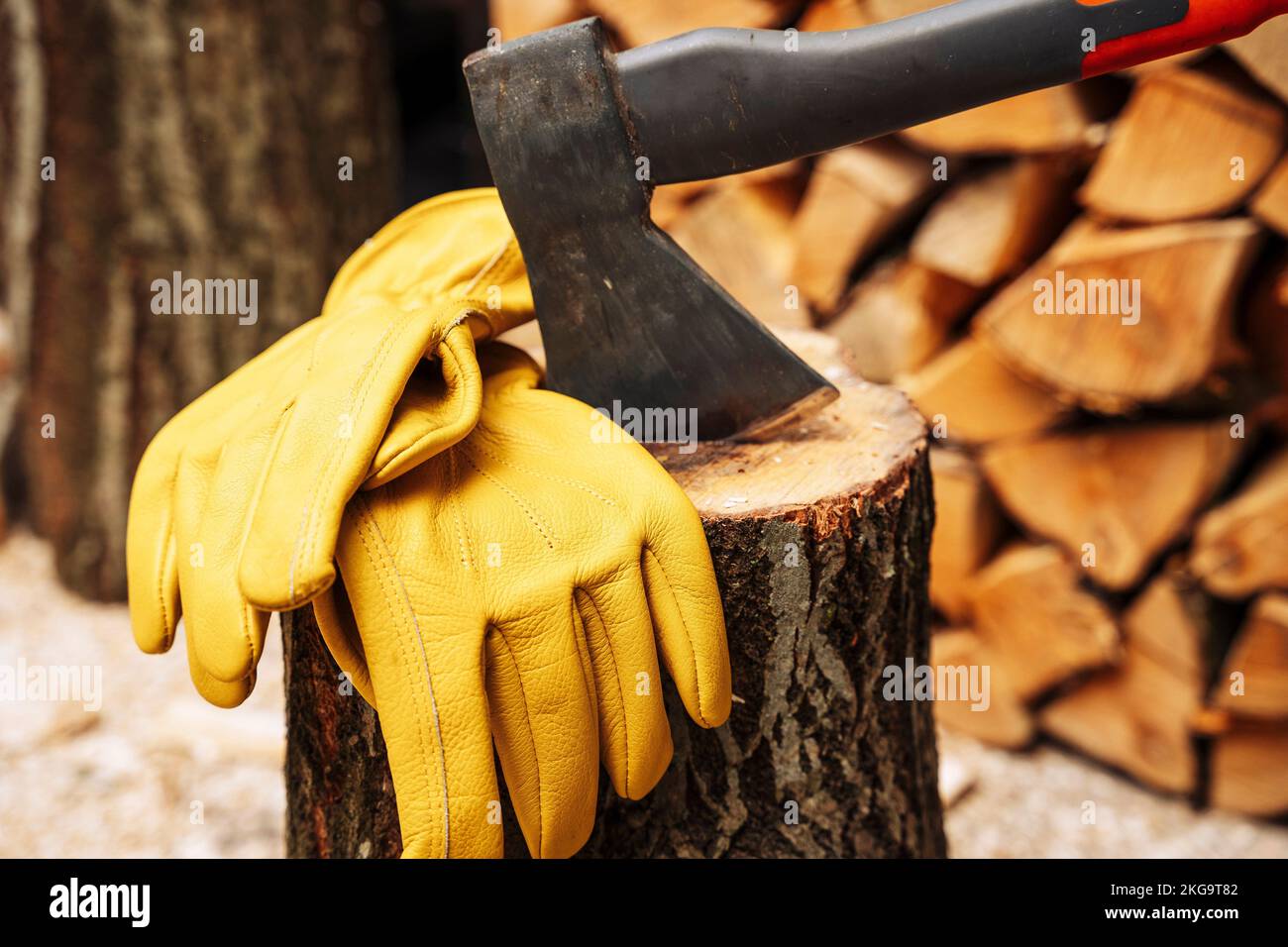 axe stuck in a wooden deck and protective yellow leather gloves Stock