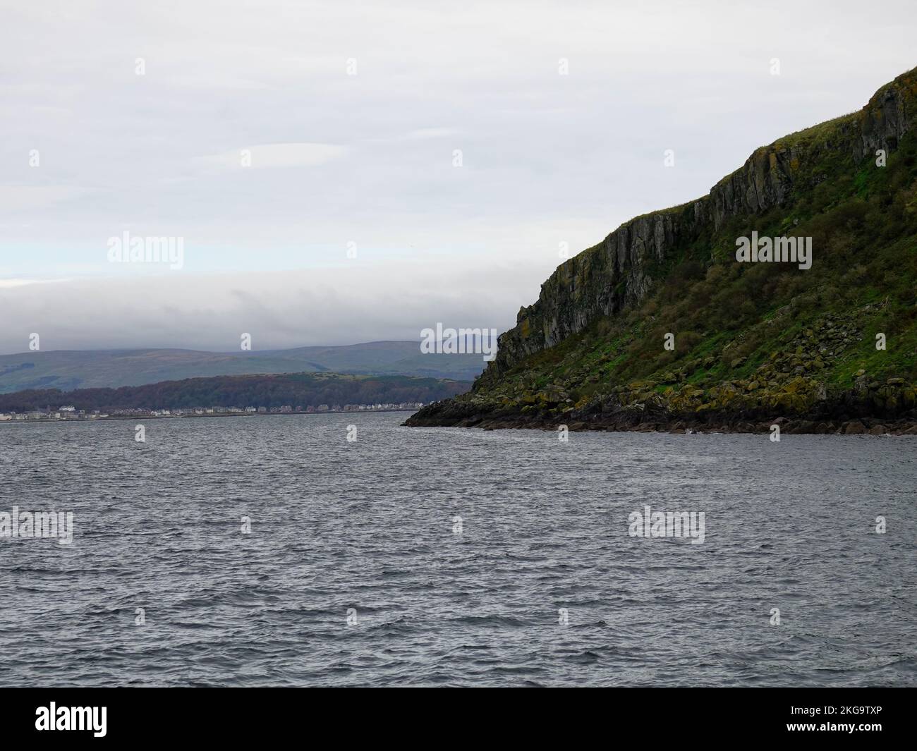 North end of Little Cumbrae Island, cloudy, foggy day, with rolling hills, buildings, houses in the distance, Scotland, UK. Stock Photo