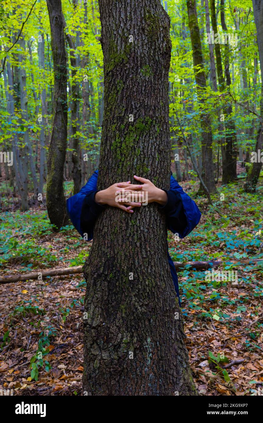 Woman giving a hug to the tree in the forest. Environmental activism concept photo. World Environment Day or Earth Day background vertical photo. Stock Photo