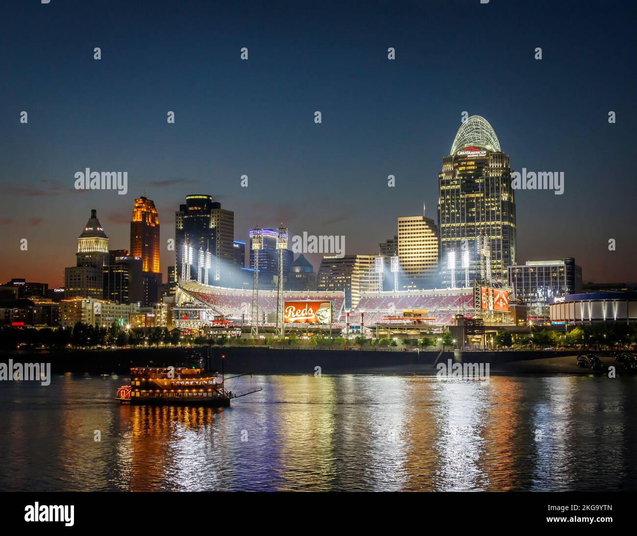 Cincinnati, Ohio, skyline at dusk. Cincinnati Reds baseball sign and stadium near center. Belle of Cincinnati Riverboat, sternwheeler, in the foregrou Stock Photo