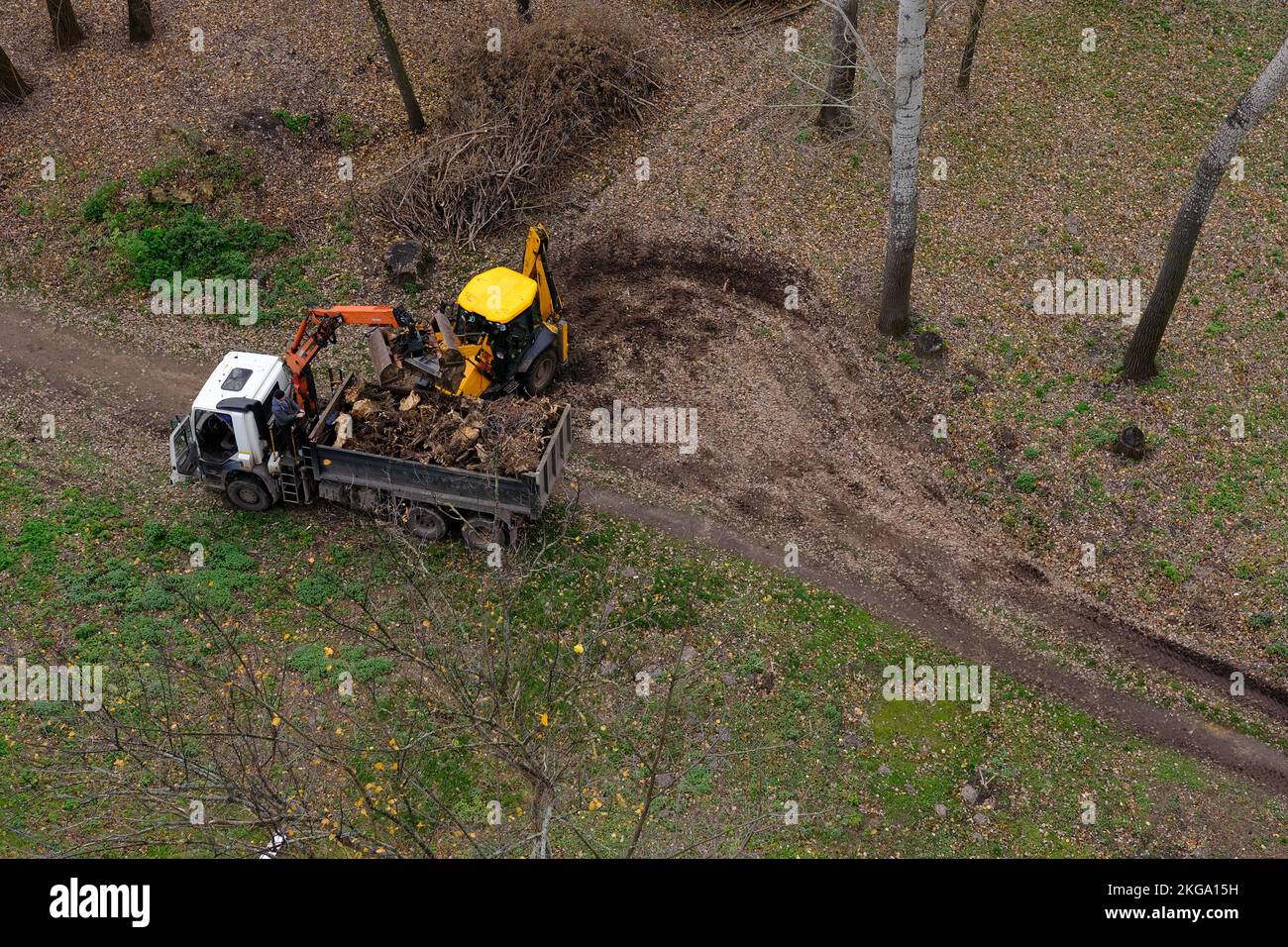 Landscaping company using tractor and truck with crane to clear land of