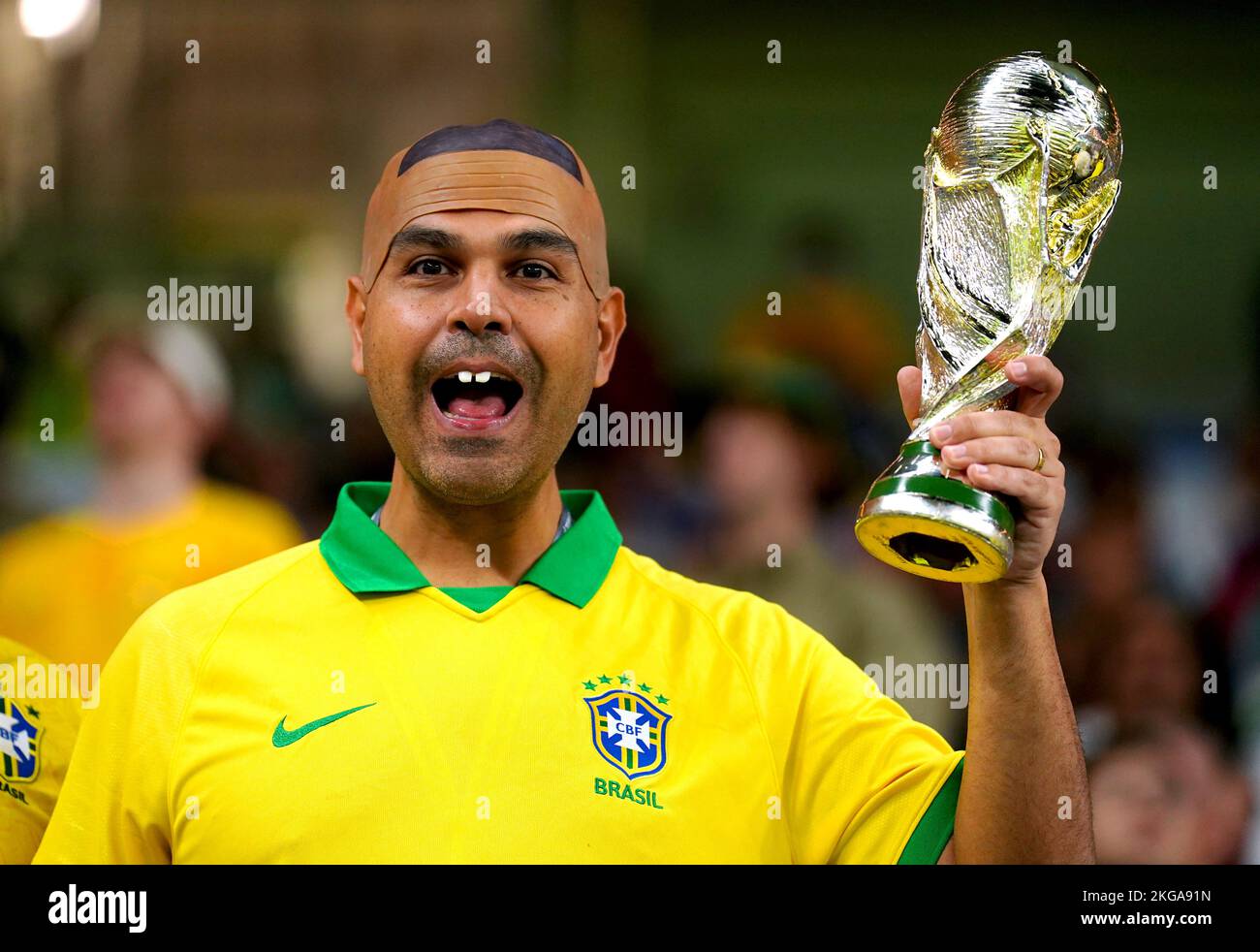 A Brazil fan dressed as former Brazil footballer Ronaldo, holds up a replica of the FIFA World Cup trophy ahead of the FIFA World Cup Group D match at Al Janoub Stadium, Al Wakrah. Picture date: Tuesday November 22, 2022. Stock Photo