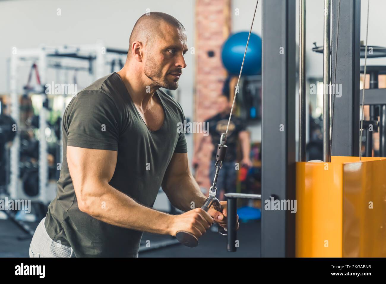 Strong, muscular, handsome bald man, bodybuilder, performing cable tricep extensions in the gym. High quality photo Stock Photo