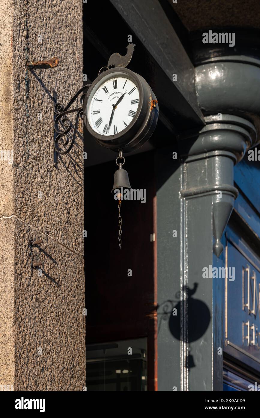 22 November 2022. Grantown on Spey,Scotland. This is a Grosvenor Clock Co, Clock and shadow outside a shop in the town main street. Stock Photo