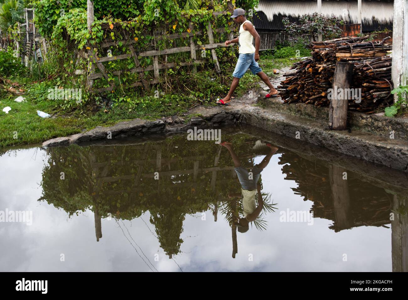Reflection of a man in the water of the river. He walks through the top. City of Aratuipe, Bahia, Brazil. Stock Photo