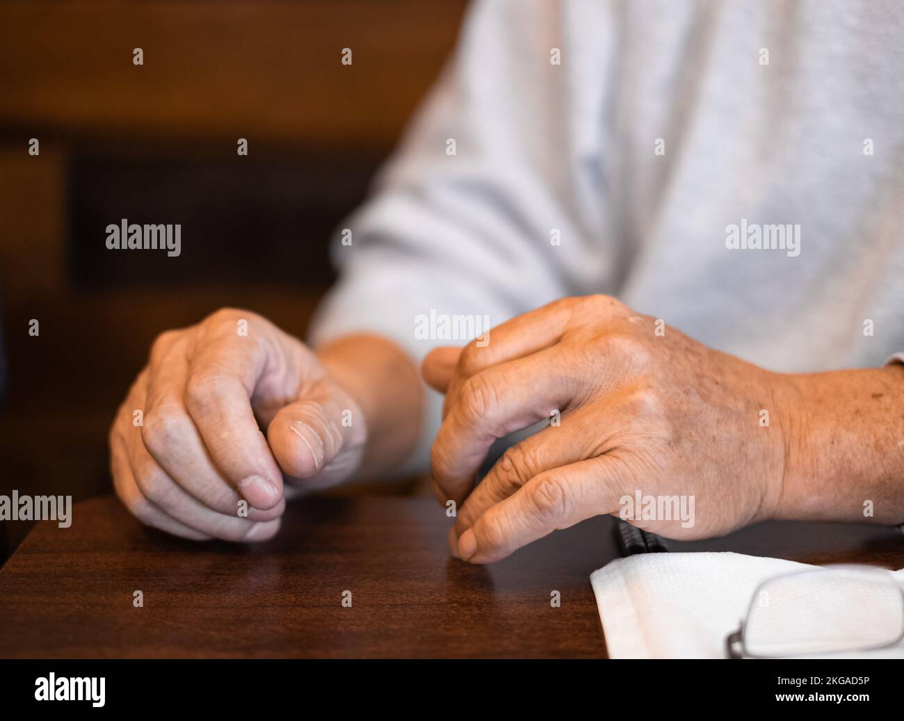 Man hands resting on a wooden table. Close up of Hands of a man. Male hands. Selective focus, blurred Stock Photo