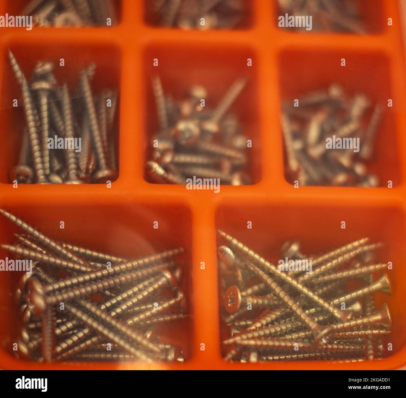 Plastic transparent organizer with screws, dowels, drills. Screws and nails in orange plastic box. Plastic organizer box with wood screws and nails. A Stock Photo