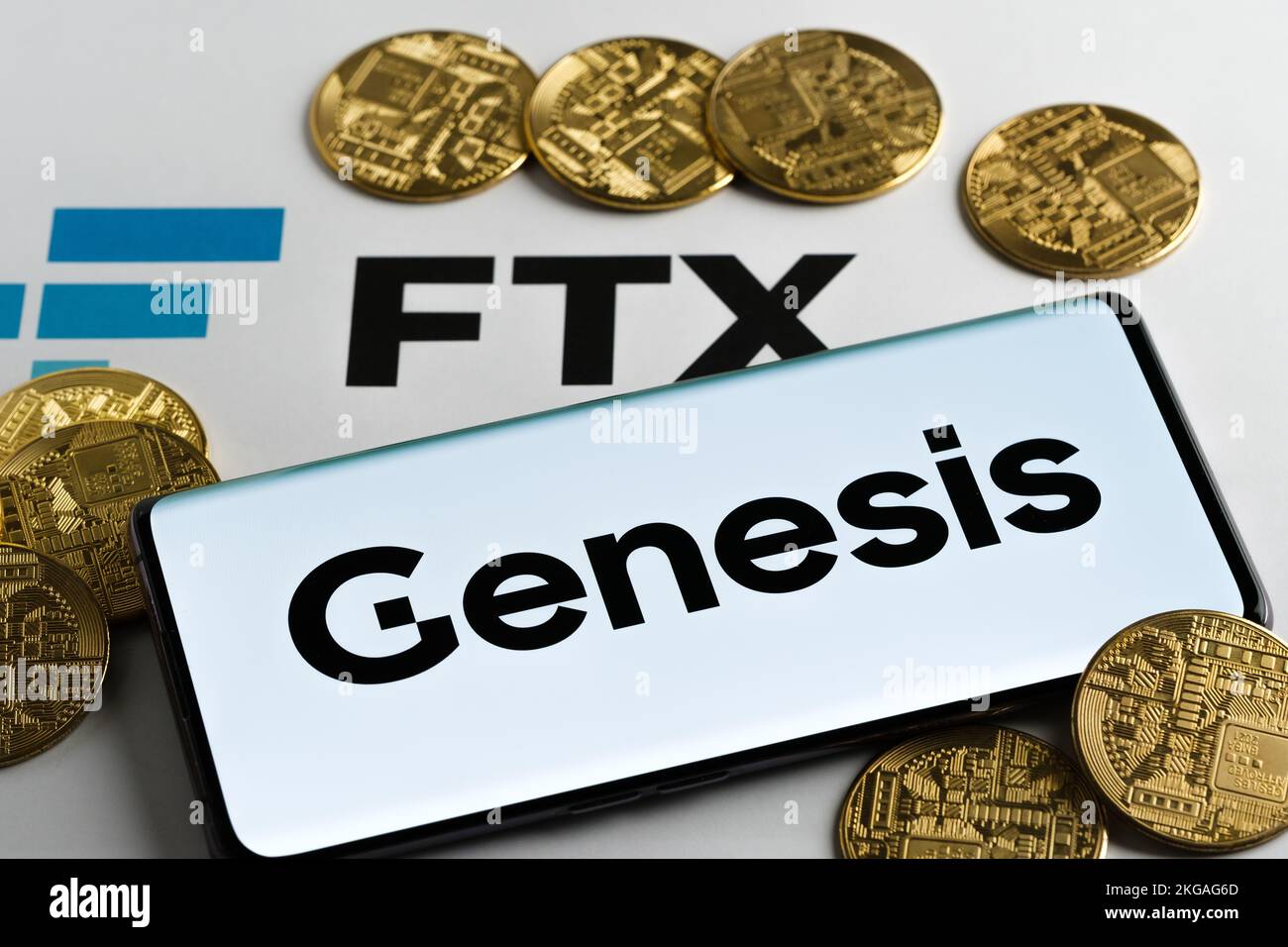 FTX and Genesis concept. Genesis Trading crypto company logo seen on screen of the smartphone surrounded by tokens and FTX logo printed on paper. Staf Stock Photo