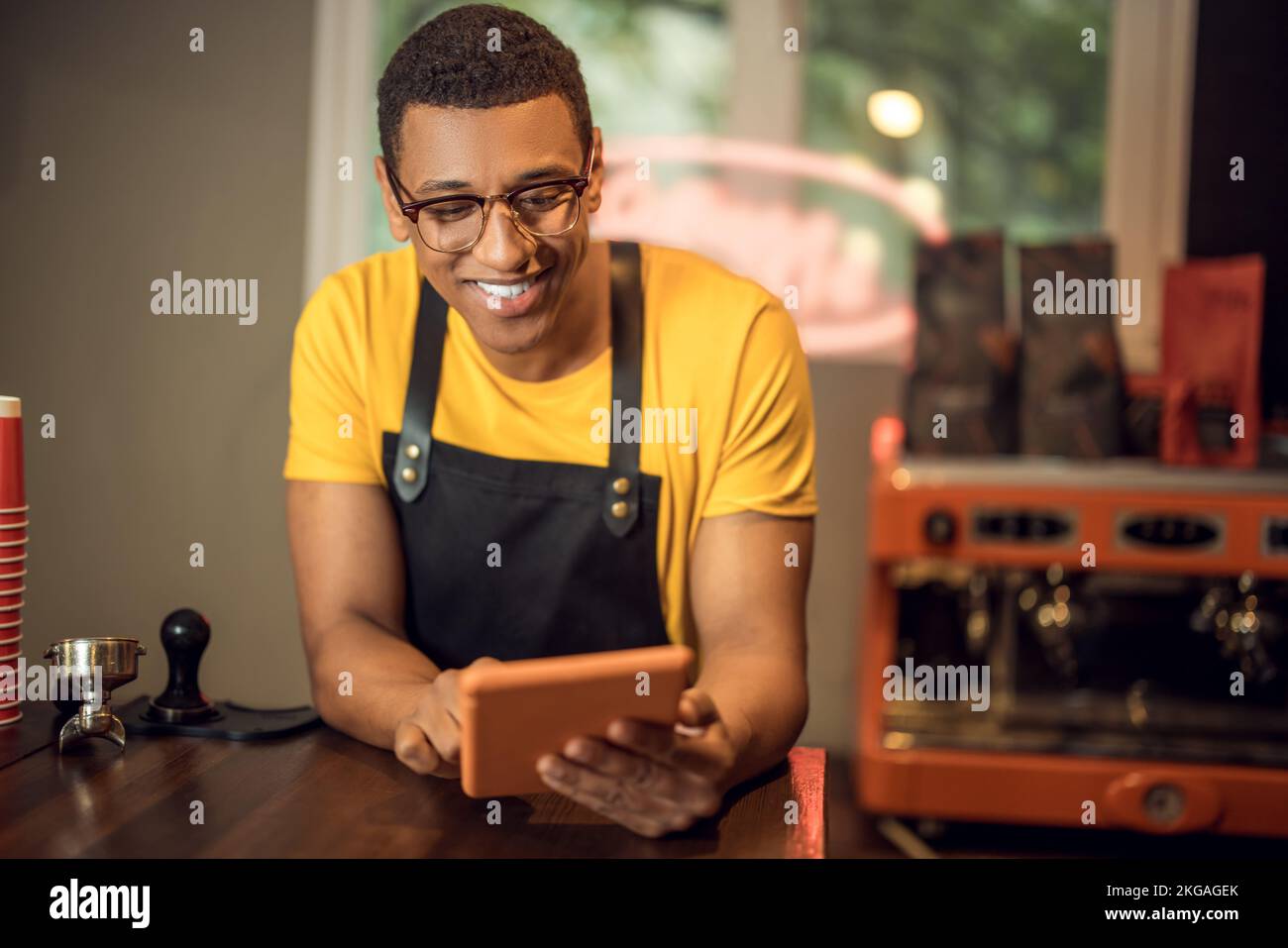 Cheerful coffee shop worker using a gadget in the workplace Stock Photo