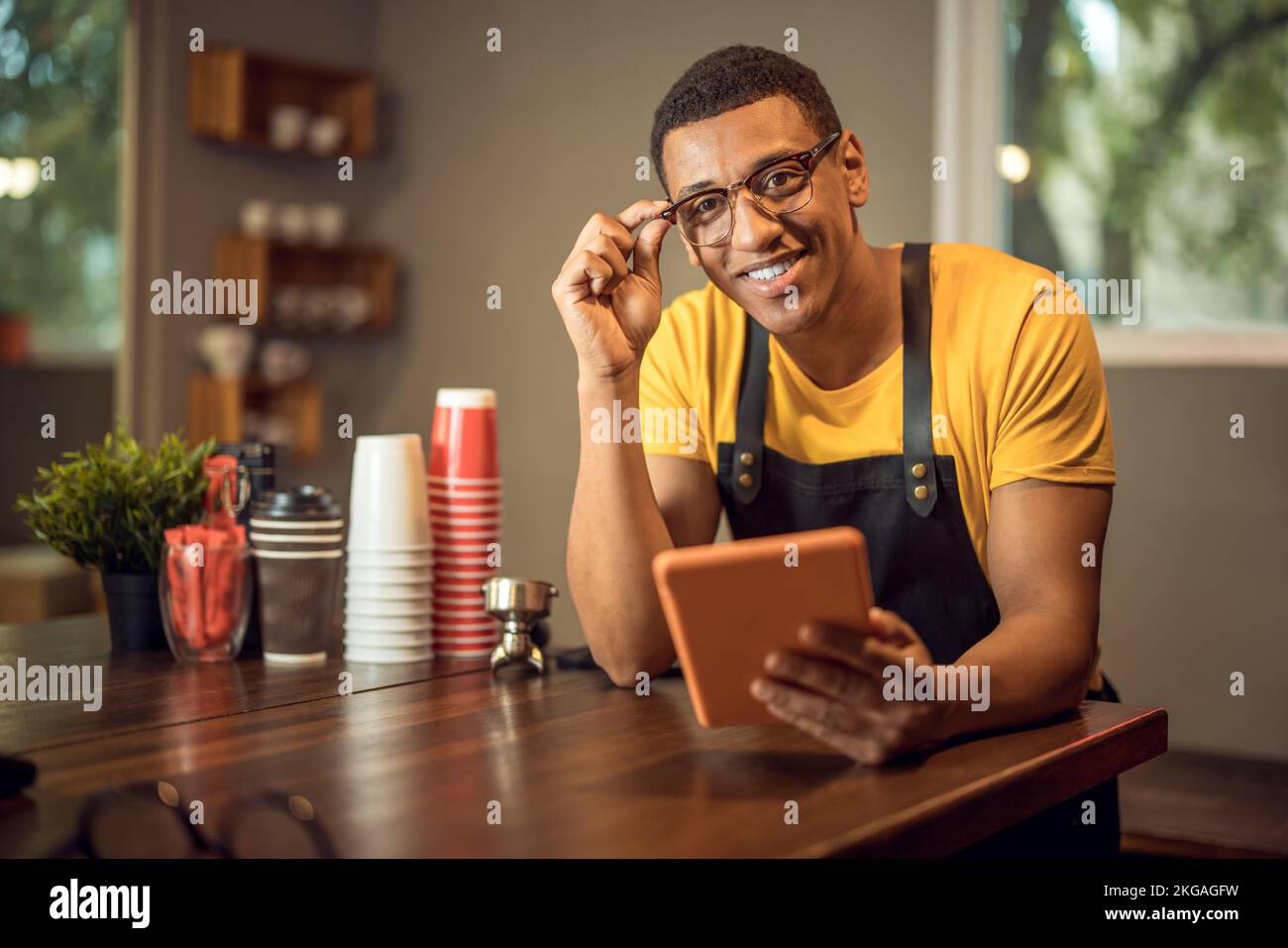 Smiling happy coffee shop worker seated at the table Stock Photo