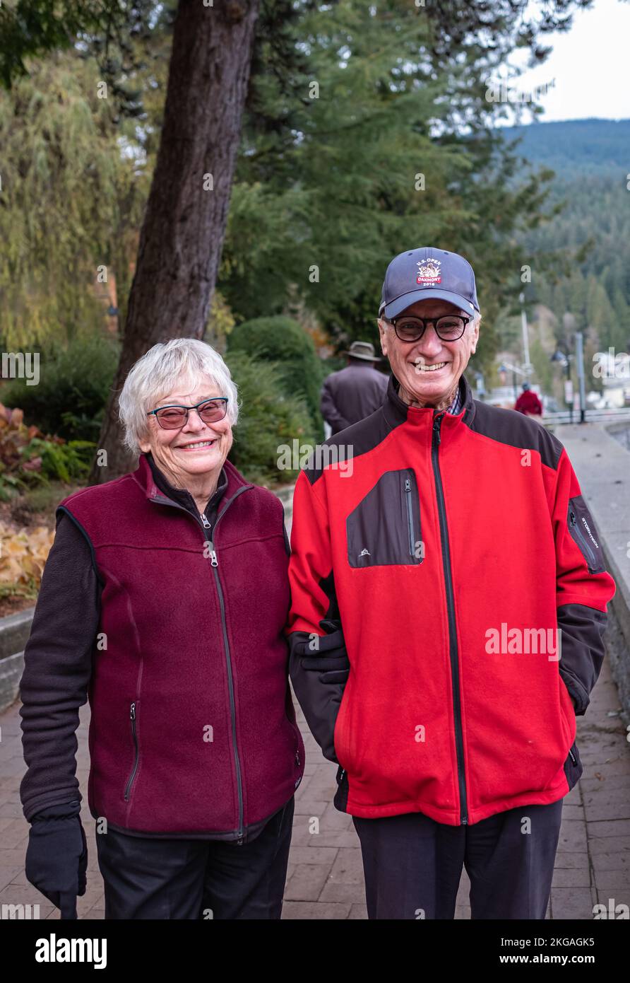 Smiling happy senior couple walking in the park. Senior couple walking in cold autumn day. Happily retired and Elderly healthy lifestyle concept-Novem Stock Photo