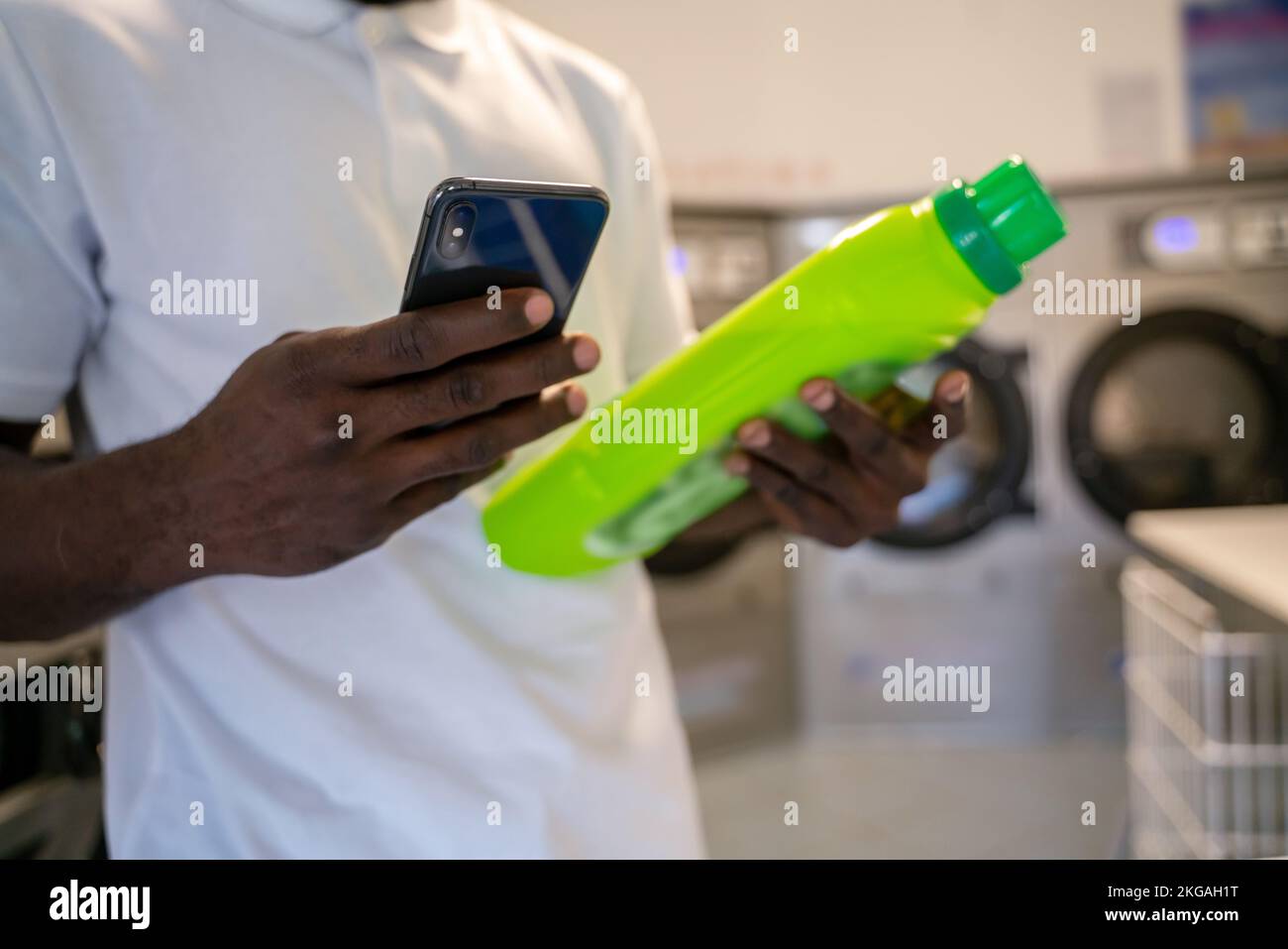 Adult man using the mobile phone at a launderette Stock Photo