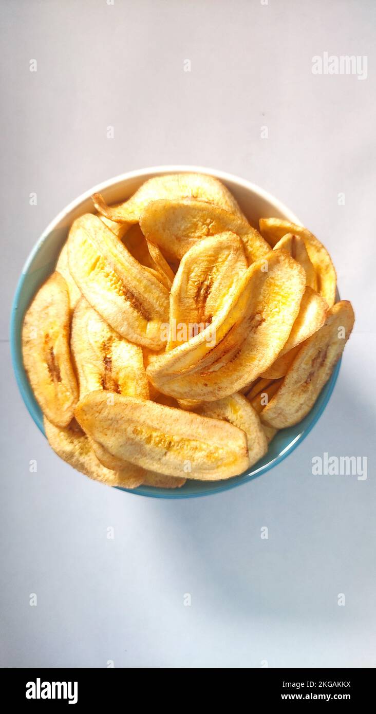 Banana chips in a blue white bowl on a white background ready for sale