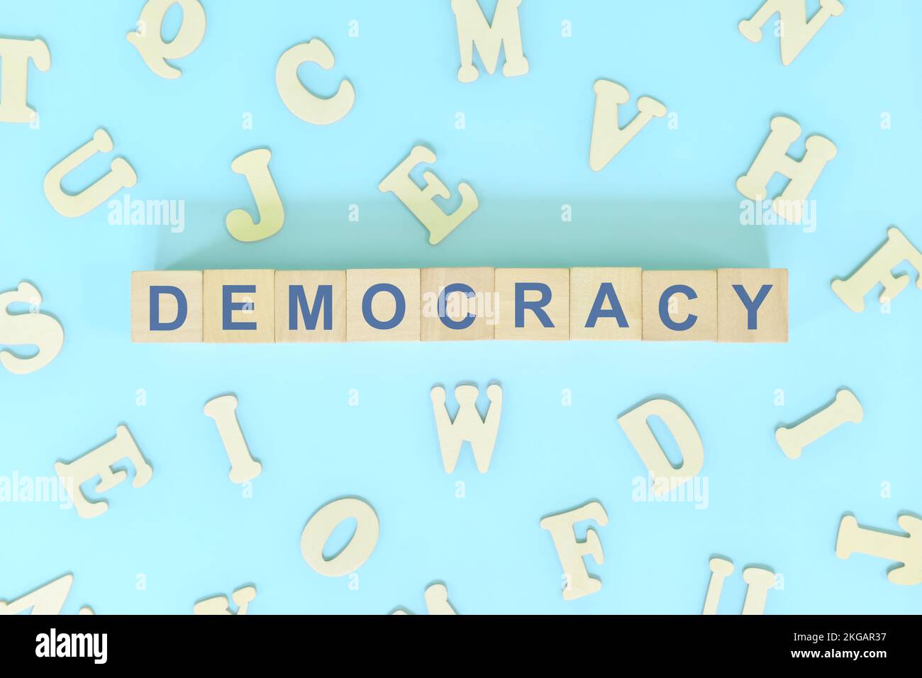 Democracy government form concept. Wooden blocks typography flat lay in blue background. Stock Photo