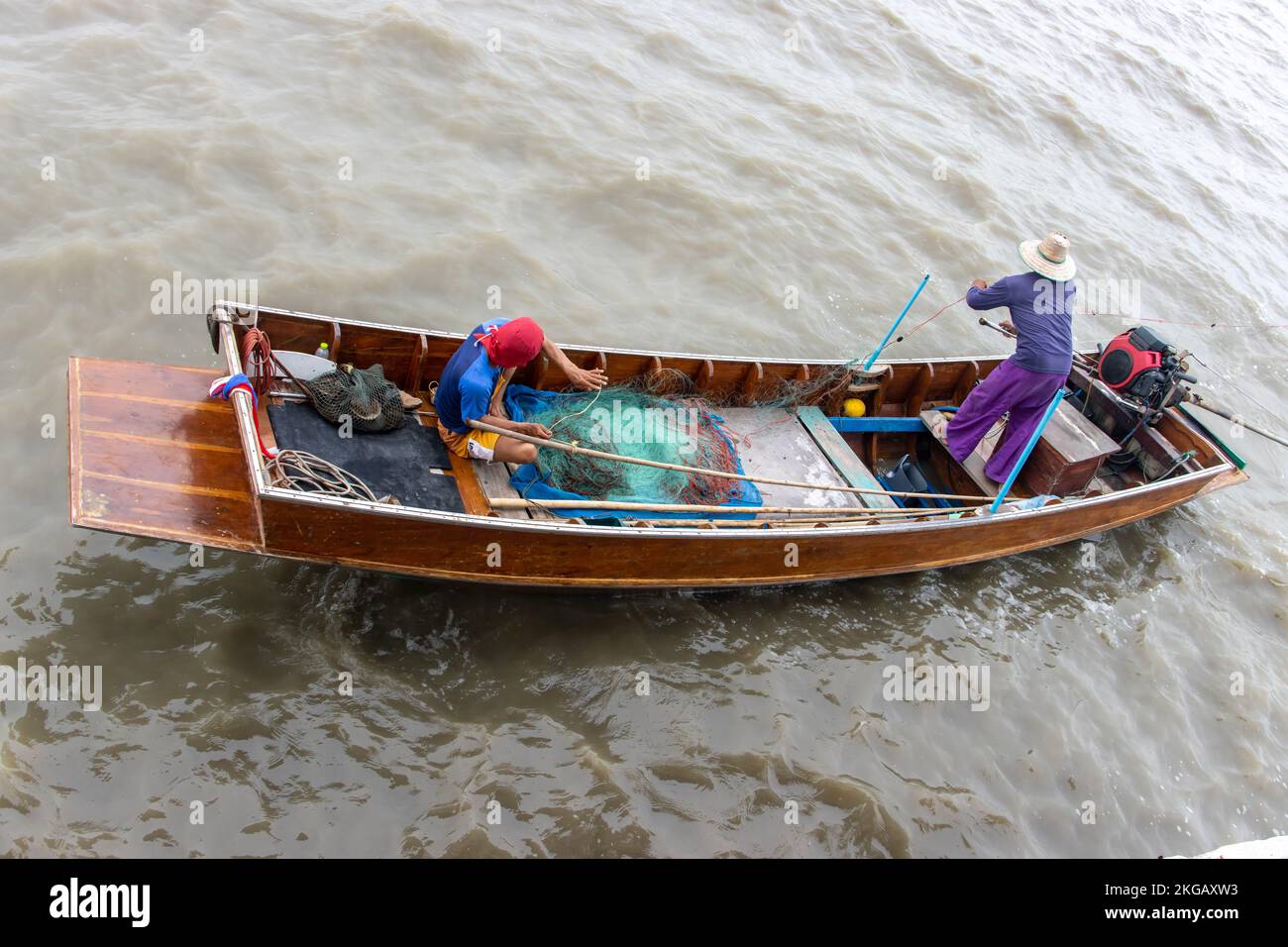 Asian fishermen sail on a boat and throw their nets into the water