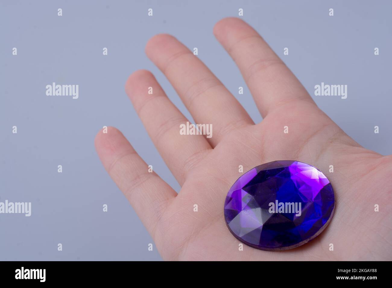 Hand holding a purple diamond on a white background Stock Photo