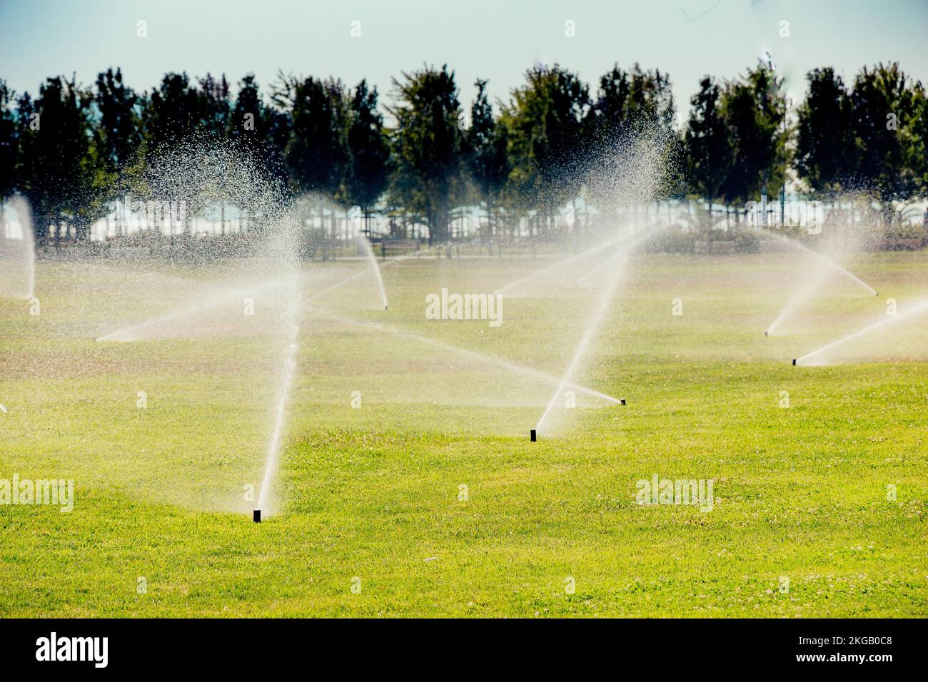Lawn water sprinkler spraying water over grass in garden Stock Photo