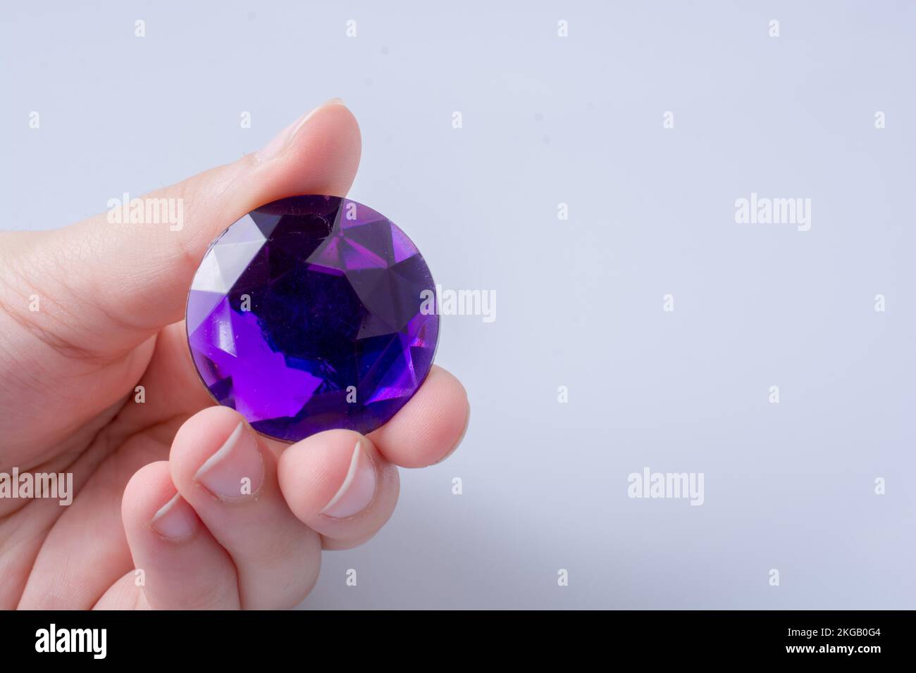 Hand holding a purple diamond on a white background Stock Photo