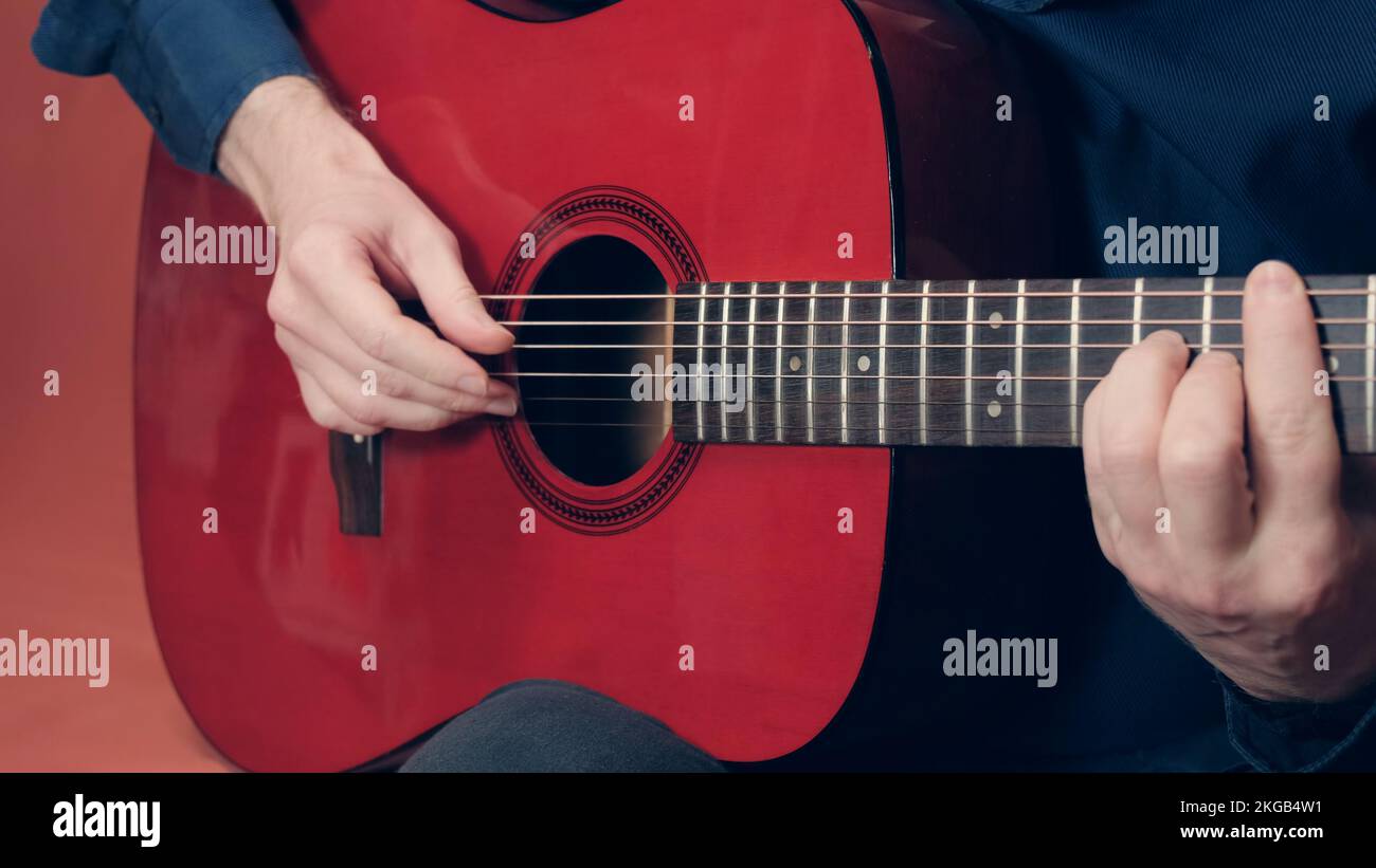 European man plays an red acoustic guitar Stock Photo