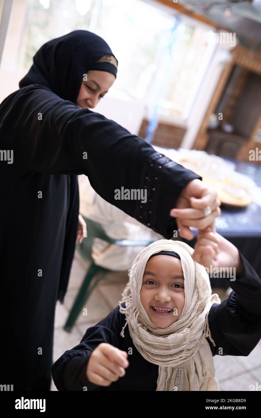 Mother and daughter closeness. A young daughter dancing with her mother - Muslim family. Stock Photo