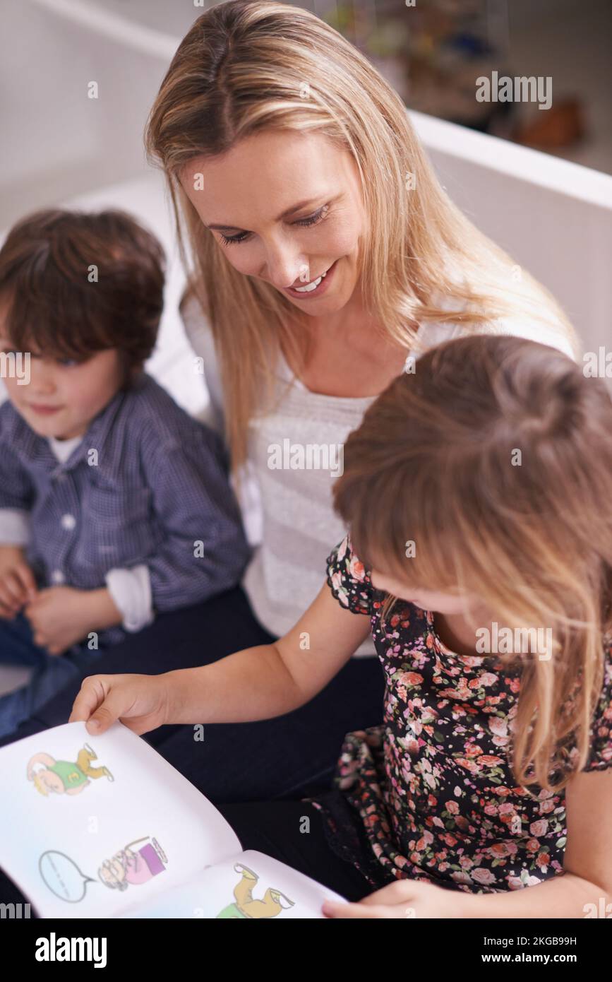 Taking a reading adventure. a mother reading with her children at home. Stock Photo