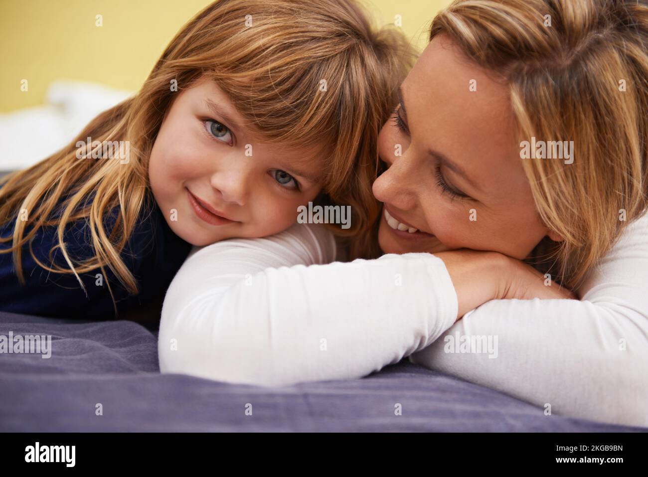Tender moments with Mom. Portrait of a little girl and her mother lying together on a bed. Stock Photo