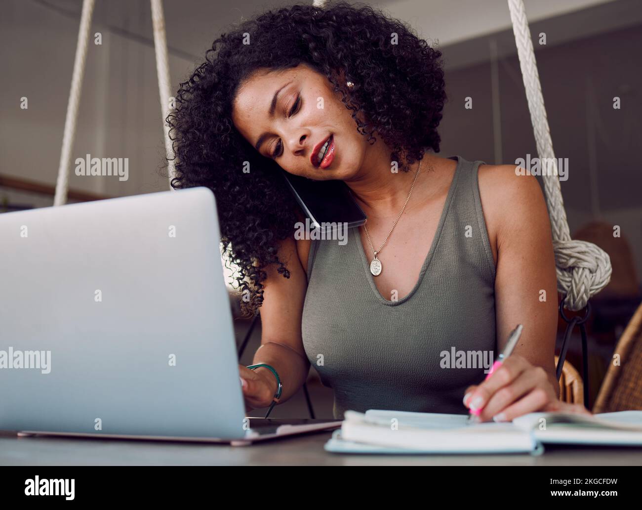 Laptop, phone call and black woman writing in notebook, multitasking and working in cafe. Freelancer, tech and female remote worker with computer Stock Photo