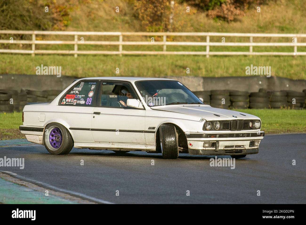 White BMW 316i 2dr saloon 1596cc; E30 3-series Rear-wheel-drive car, driving on drift tracks and high-speed cornering on wet roads on a Three Sisters Drift Day in Wigan, UK Stock Photo