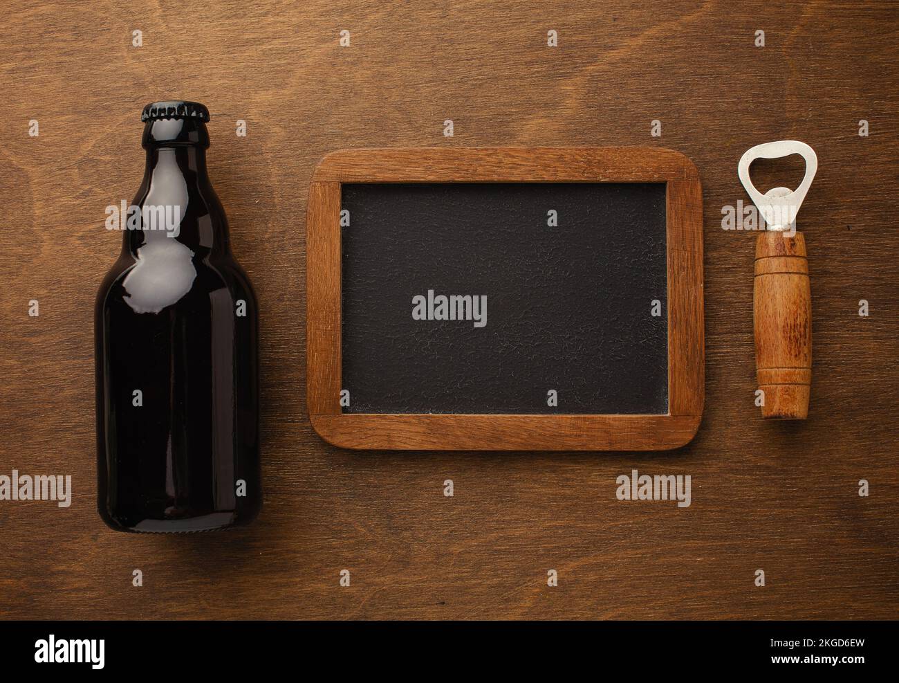 A bottle of beer on a plate with salted ookies pretzels, pistachio nuts and chips on a black scratched chalk board. Top view. High quality photo Stock Photo