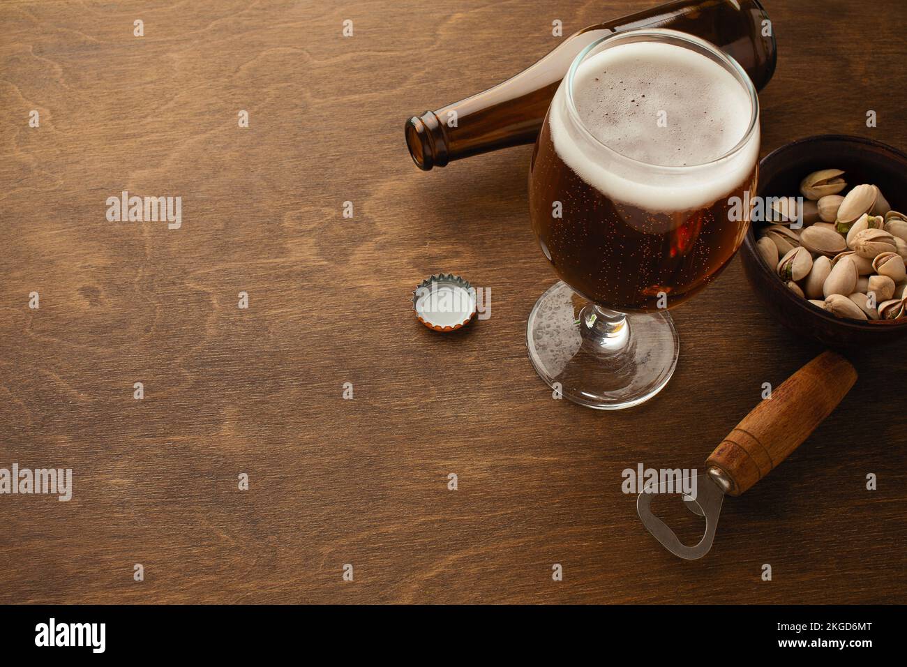 A bottle of beer on a plate with salted ookies pretzels, pistachio nuts and chips on a black scratched chalk board. Top view. High quality photo Stock Photo