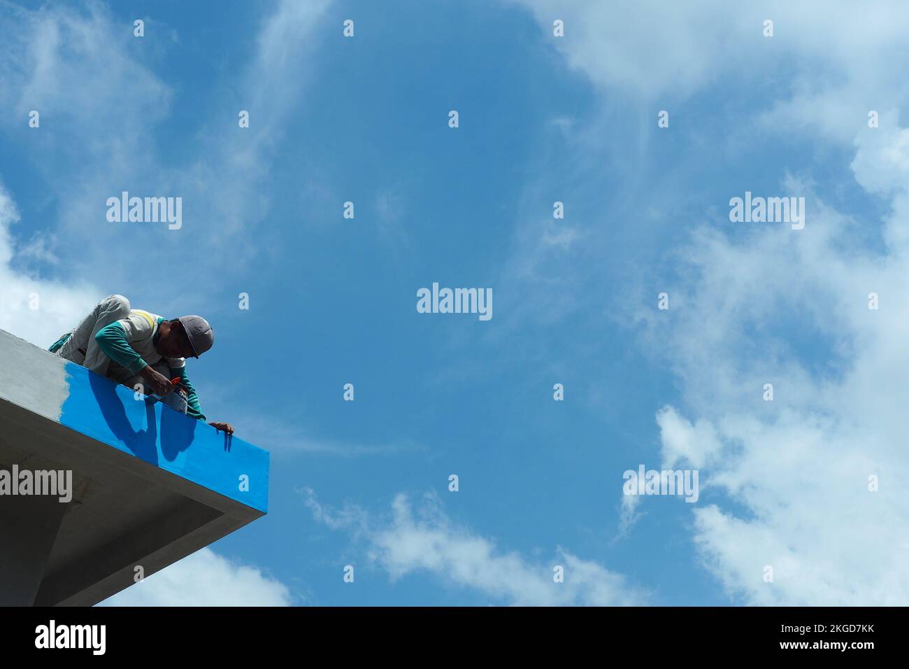 construction workers fixing roof against clouds blue sky, install shingles at the top of the house. Renovate, painting the walls, improvement, build h Stock Photo