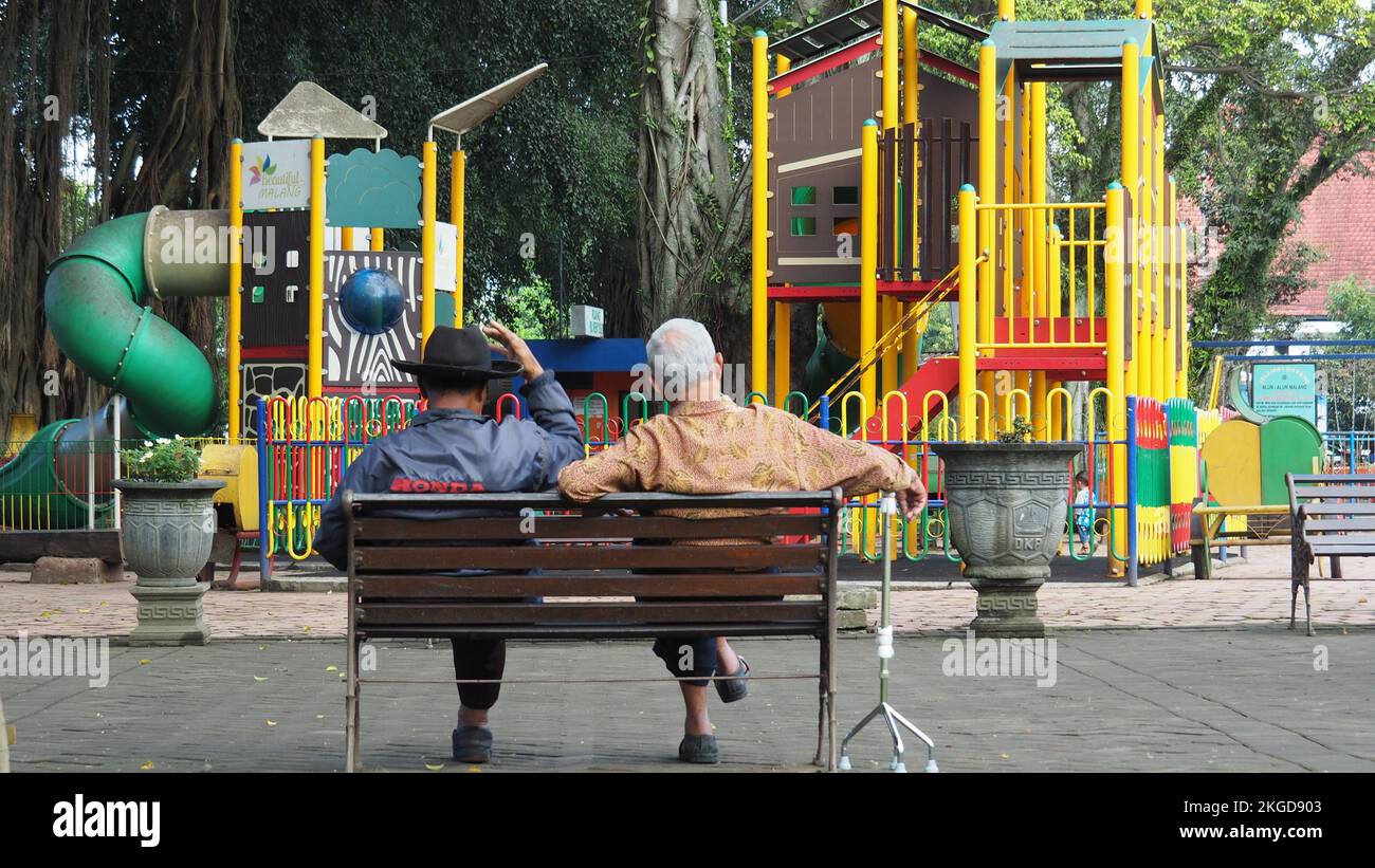Friendship to old age. Three adults sit in chairs in the Alun-alun Malang city of East Java. MALANG, INDONESIA. MARCH 08, 2018. Stock Photo