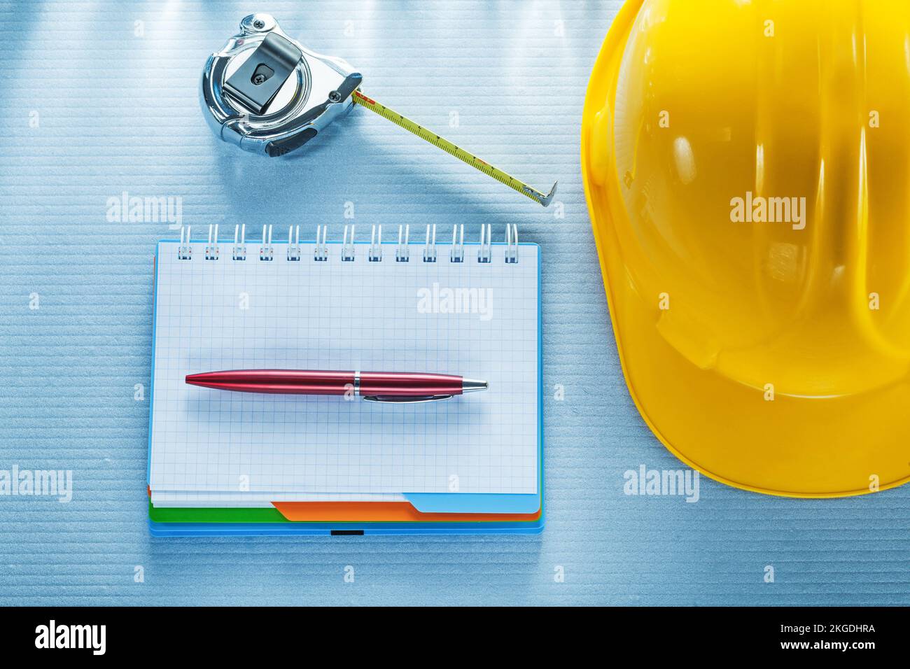 Checked notebook pen hard hat measuring tape. Stock Photo