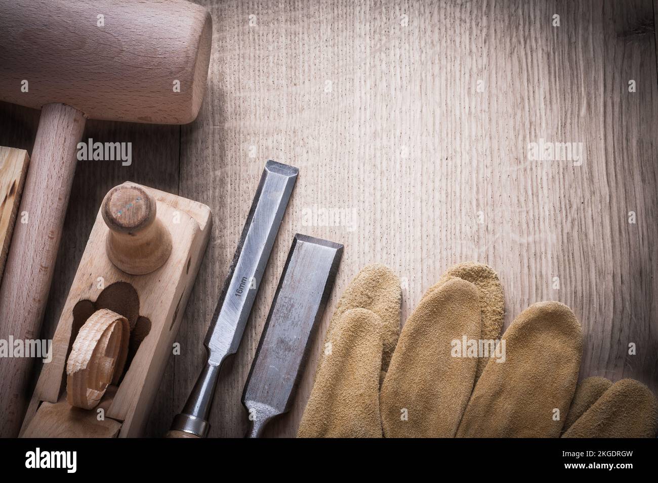 Composition of wooden bricks mallet shaving plane chisels leather gloves on wood background construction concept. Stock Photo